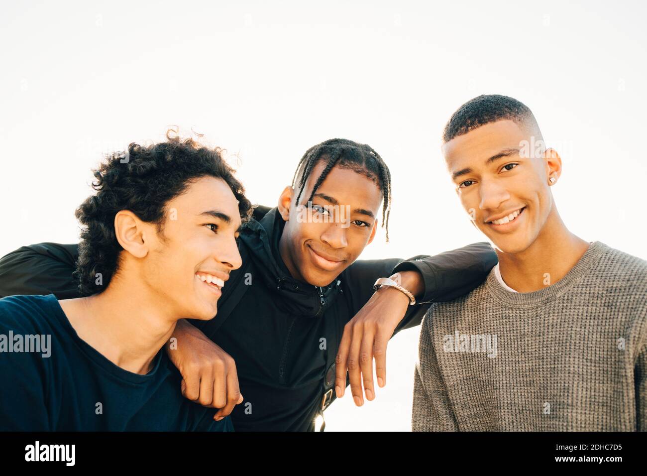 Portrait von lächelnden Teenagern mit Freund gegen klaren Himmel Stockfoto