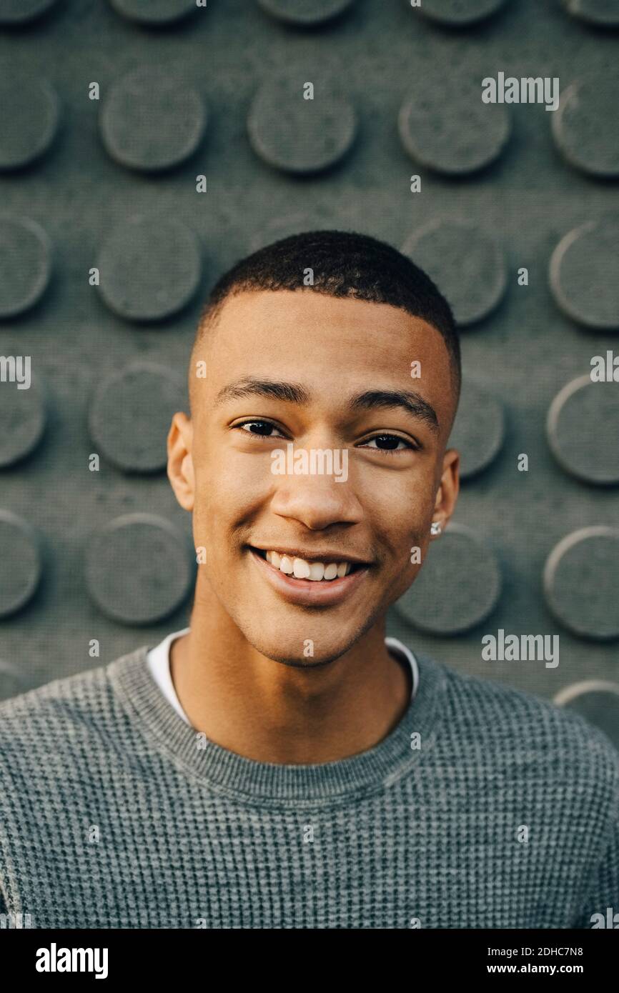 Porträt eines lächelnden Jungen im Teenageralter, der gegen die Wand steht Stockfoto