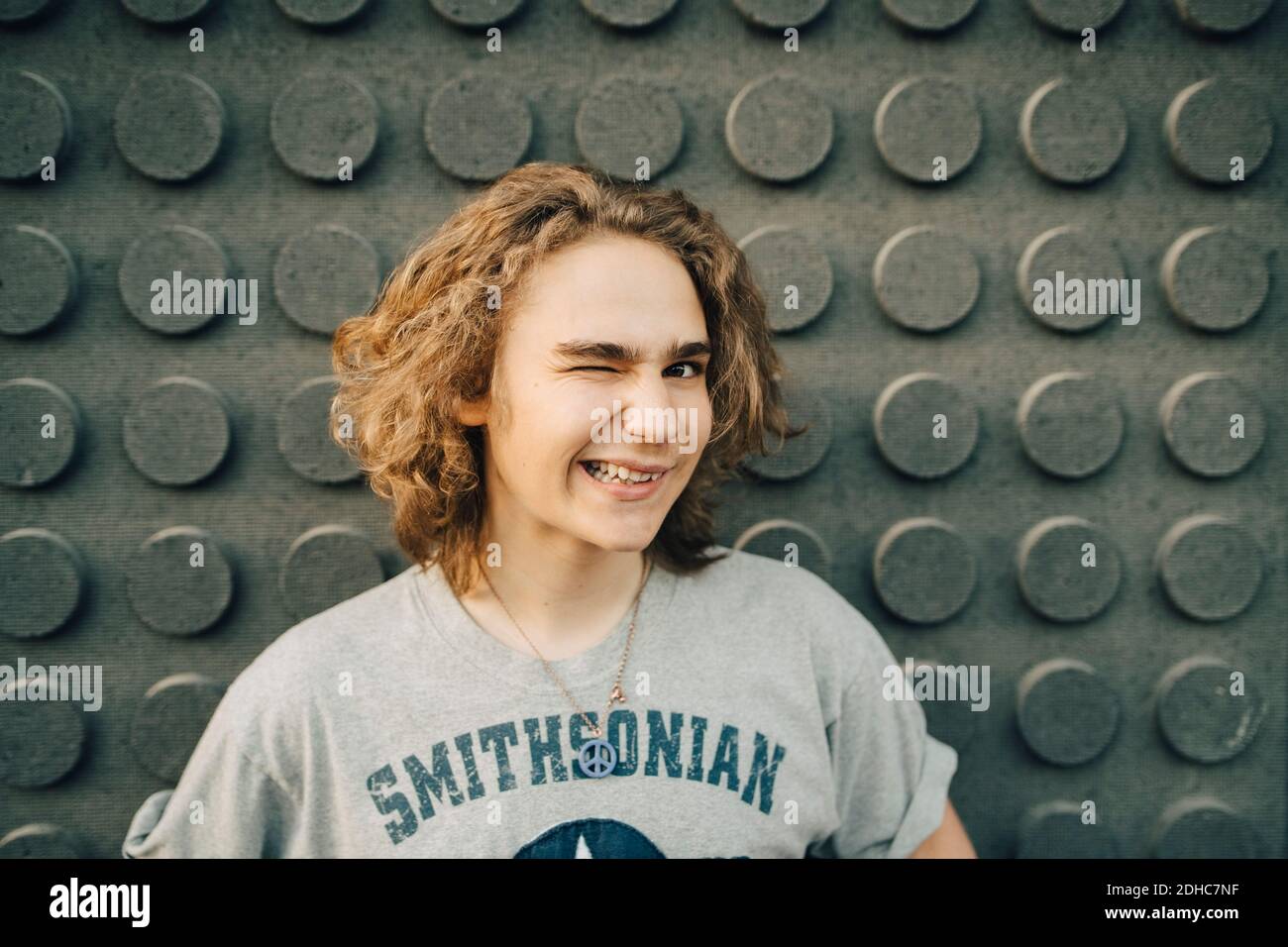 Porträt eines lächelnden jungen Mannes, der gegen die Wand zwinkert Stockfoto