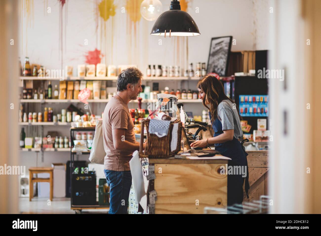 Seitenansicht der Verkäuferin mit dem Kunden beim Auschecken Theke im Deli Stockfoto