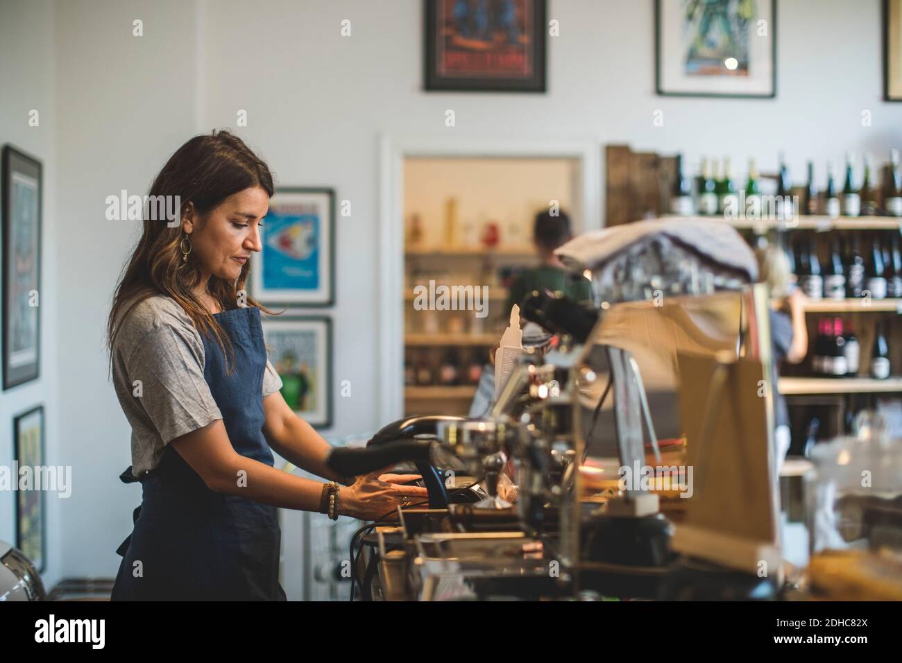 Seitenansicht der Verkäuferin, die an der Kasse arbeitet Im Feinkostgeschäft Stockfoto