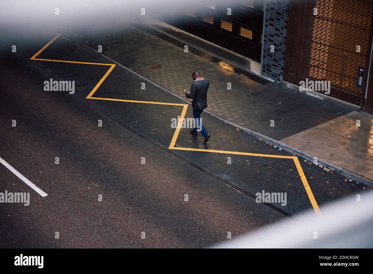 Blick auf Geschäftsmann mit Mobiltelefon während des Spazierens An der City Street Stockfoto