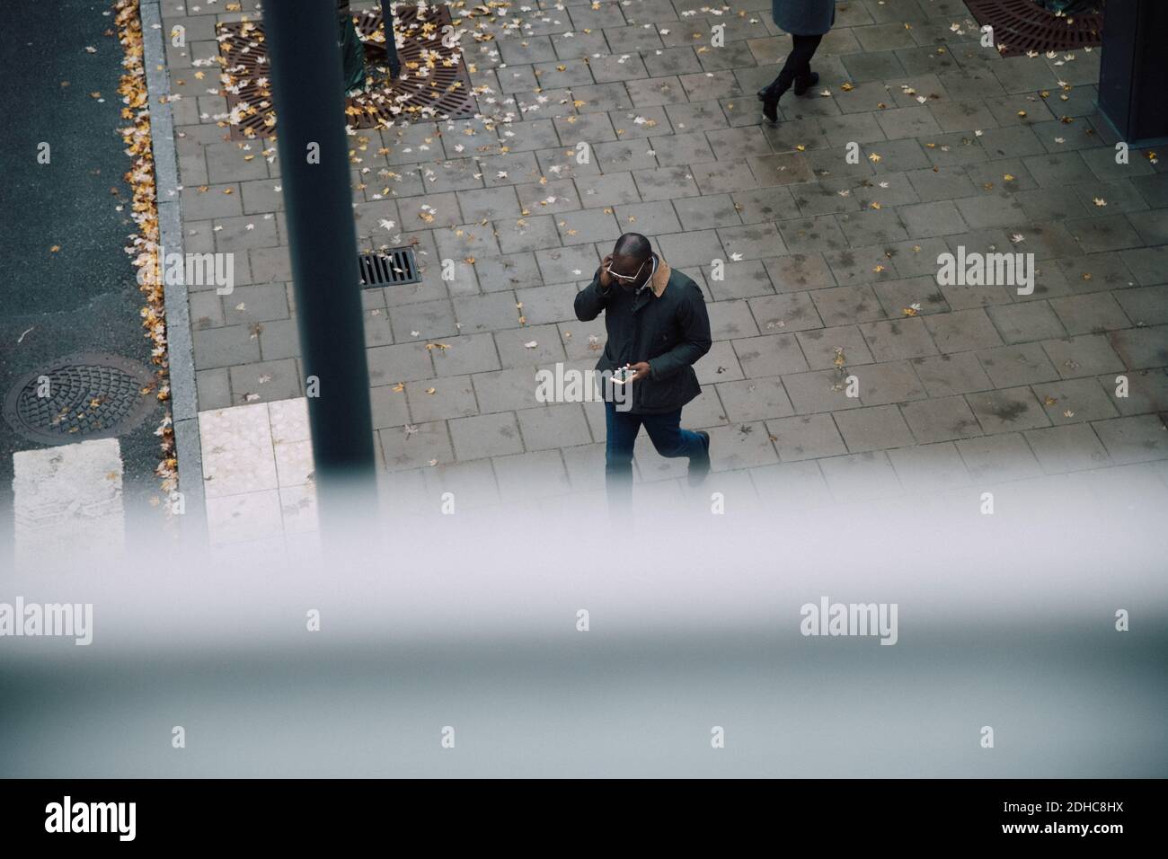 Blick auf Geschäftsmann mit Smartphone während des Spazierens An der City Street Stockfoto