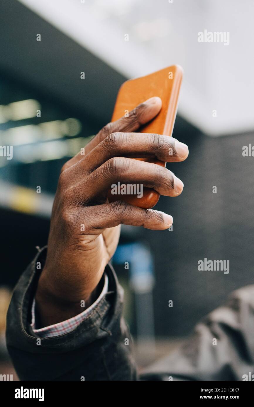 Ausgeschnittene Hand des Geschäftsmannes, der mit Smartphone gegen Gebäude fotografiert In der Stadt Stockfoto
