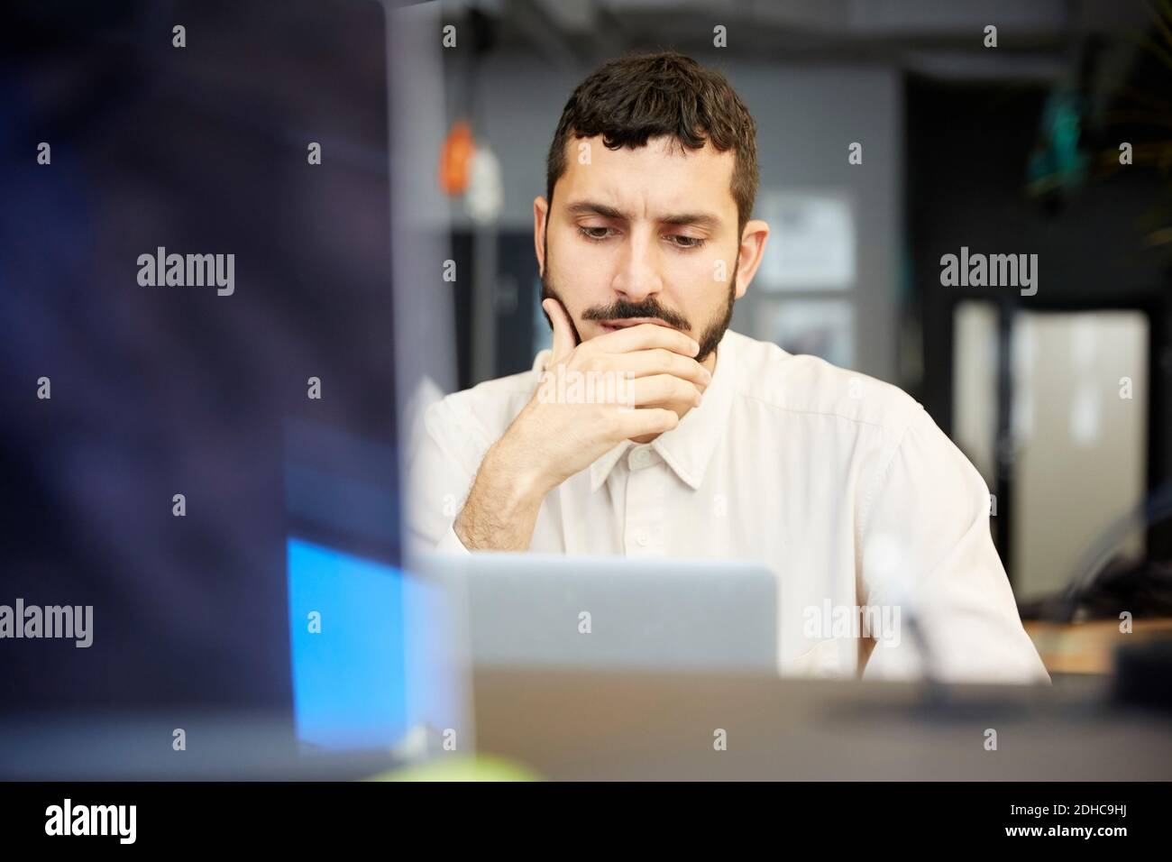 Gestresste kreative Geschäftsmann Blick auf Laptop, während im Büro sitzen Stockfoto
