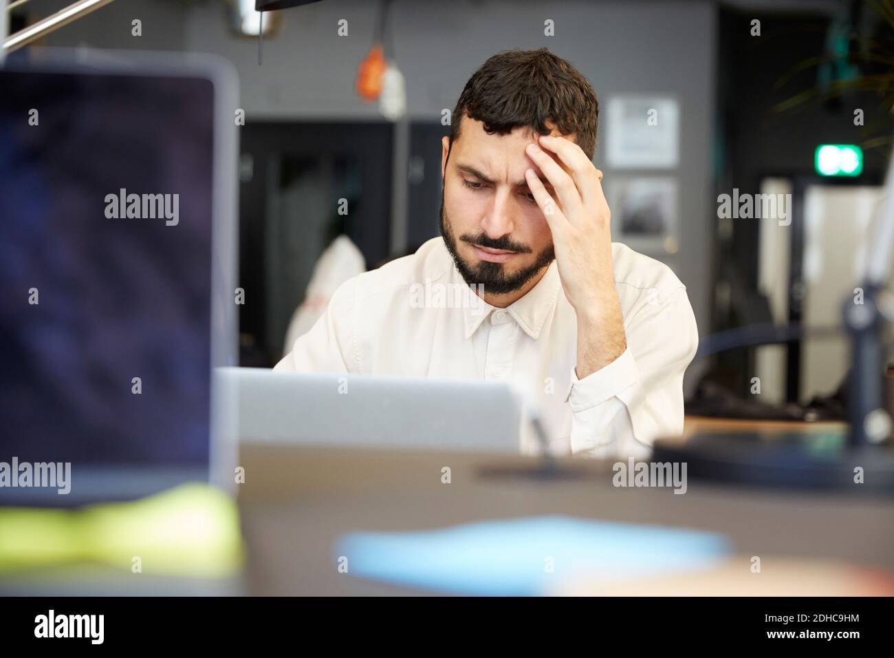 Gestresste männliche Unternehmer Blick auf Laptop, während im Büro sitzen Stockfoto