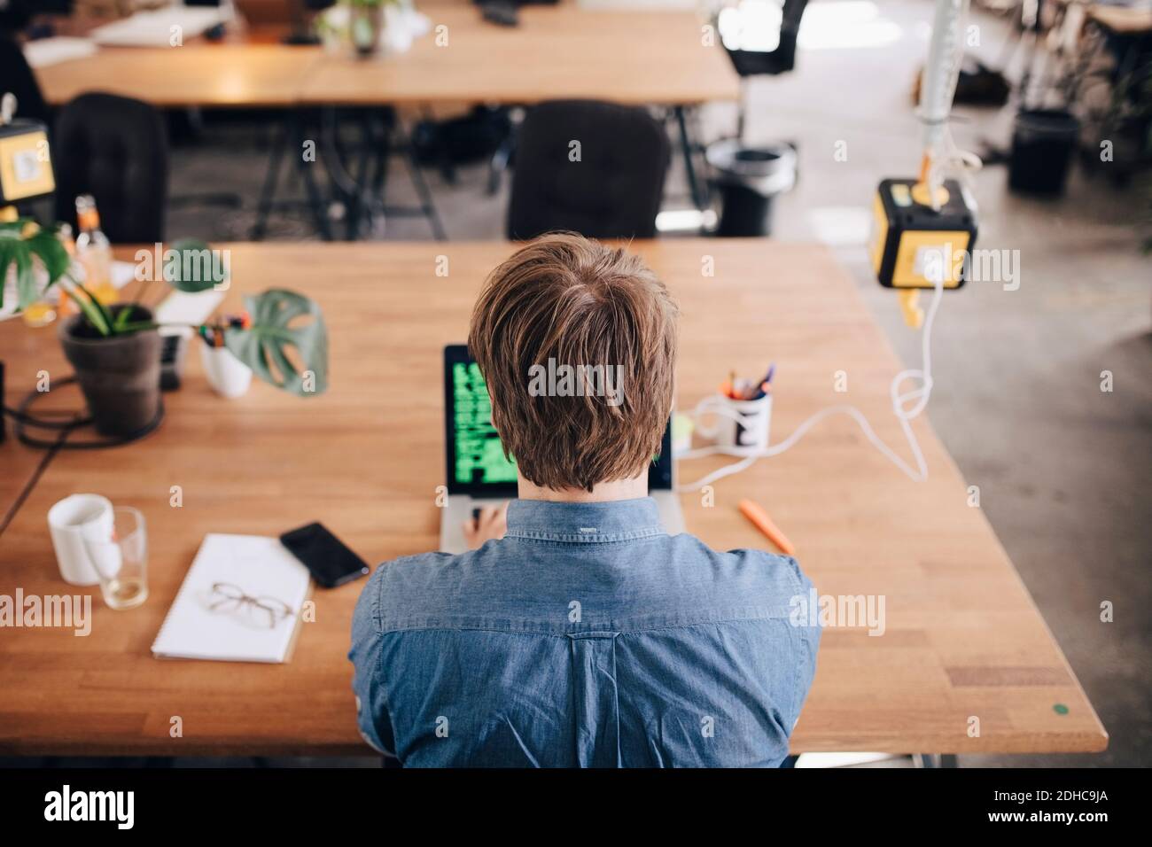 Rückansicht des Computerprogrammierers, der am Schreibtisch arbeitet, in kreativem Büro Stockfoto