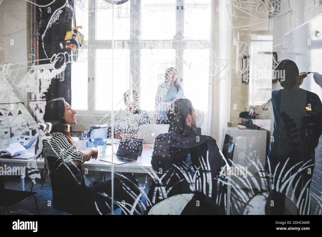 Kreative Business Professionals, die sich eine Kollegin anschaut, die die Strategie erklärt Whiteboard während der Besprechung im Büro Stockfoto