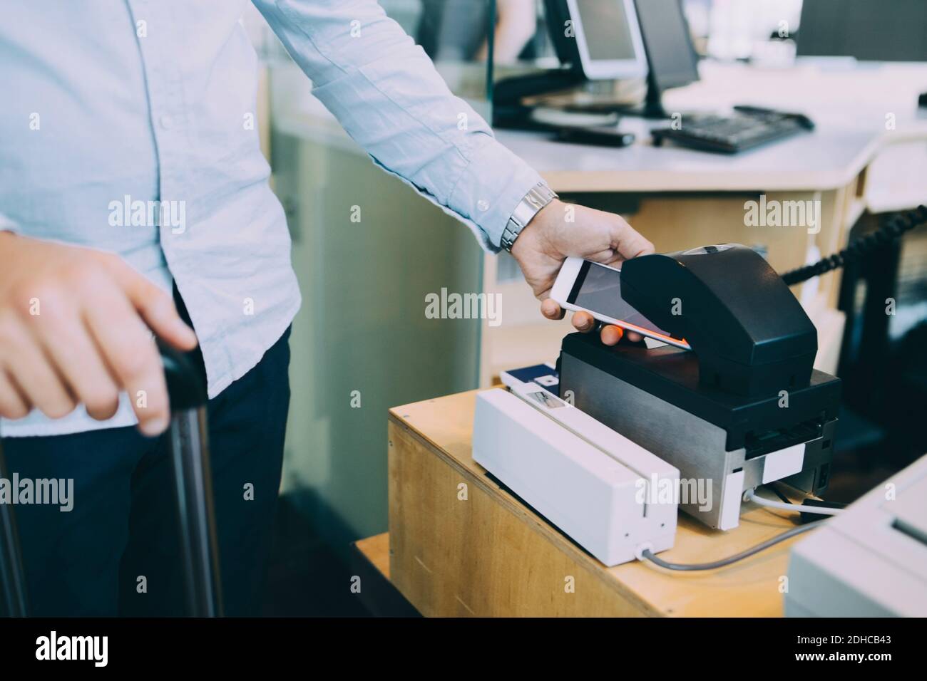 Mittelteil des Geschäftsmannes Scannen Ticket auf Smartphone am Flughafen Check-in-Schalter Stockfoto