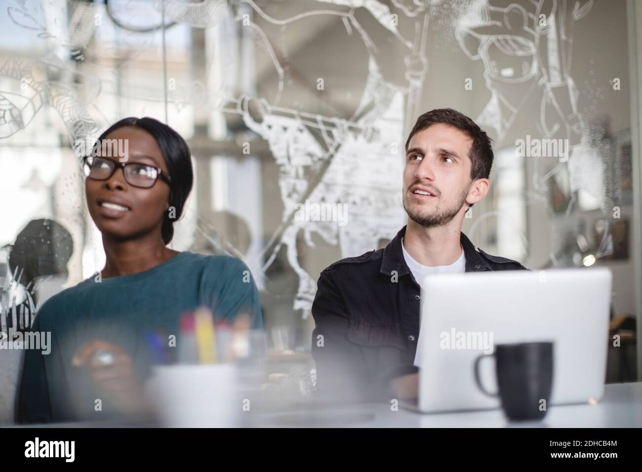 Multiethnische Kollegen hören zu, während sie an einem Konferenztisch sitzen und kreativ sind Büro Stockfoto