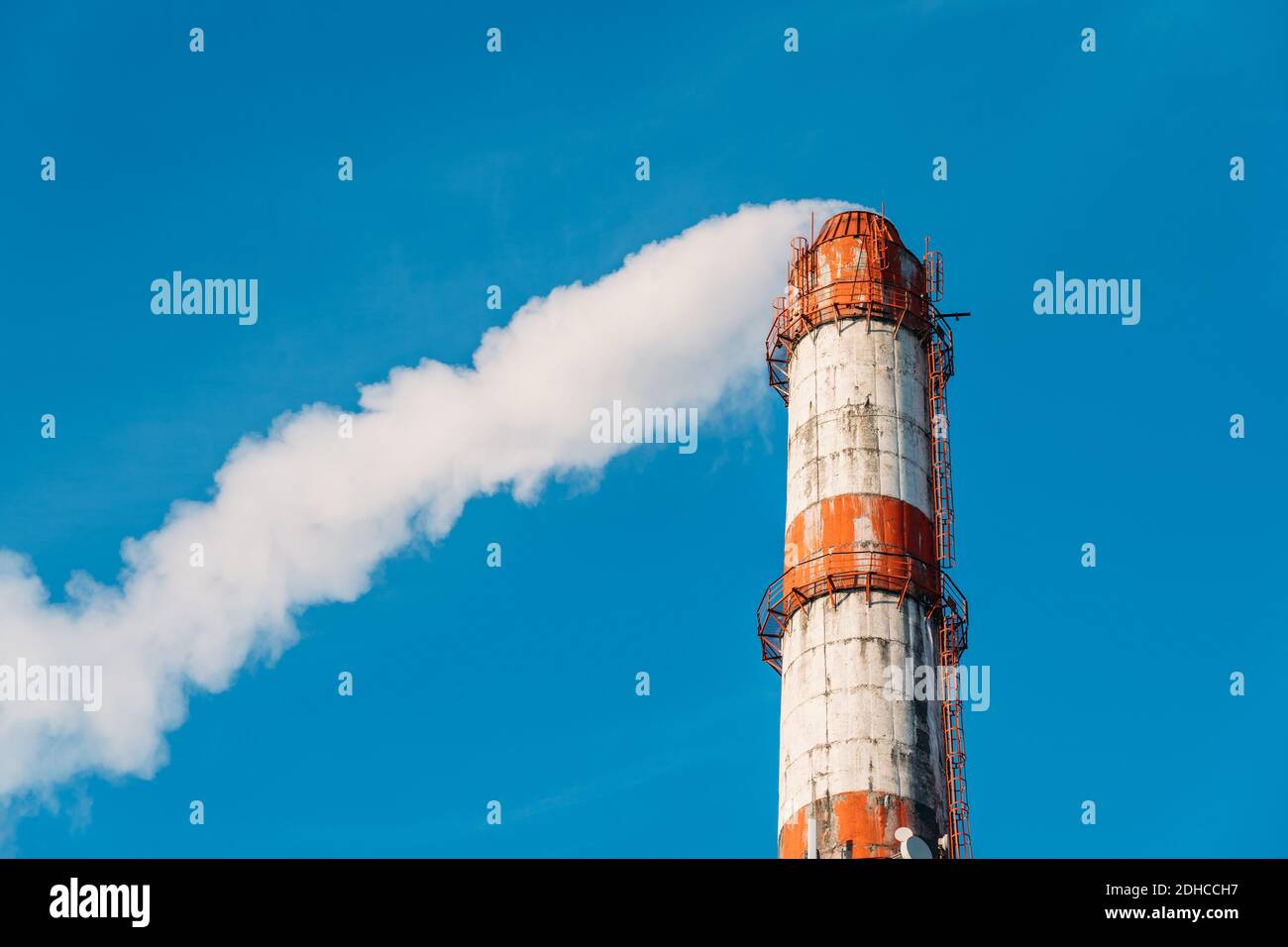Industrieller Rauchstapel der metallurgischen Fabrik mit weißem Dampf auf blauem Himmel Hintergrund. Stockfoto