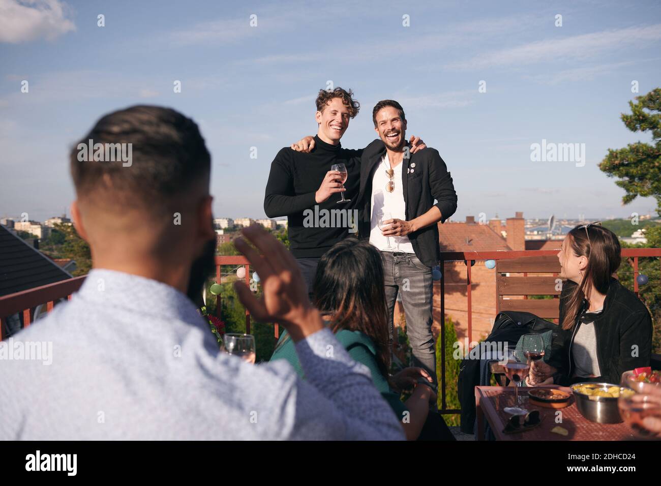 Fröhliche männliche Freunde singen beim geselligen Beisammensein auf der Terrasse Stockfoto