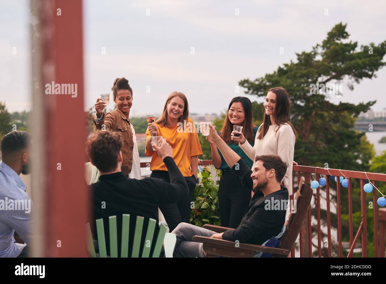 Fröhliche Freunde, die während der Party Drinks auf der Terrasse genießen Stockfoto