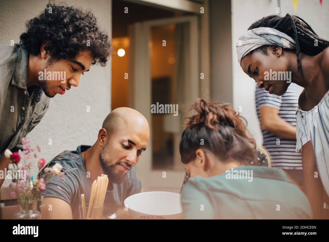 Neugierige multi-ethnische männliche und weibliche Freunde, die während des Abendessens nach unten schauen Party Stockfoto