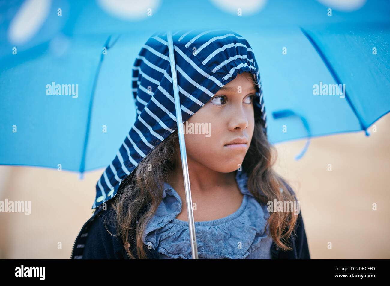 Mädchen mit Regenschirm schaut weg während der Regenzeit Stockfoto