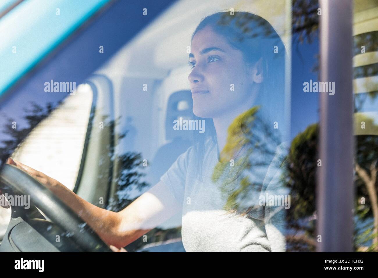 Selbstbewusste junge weibliche Besitzerin fahren Lebensmittel LKW durch Fenster gesehen Stockfoto