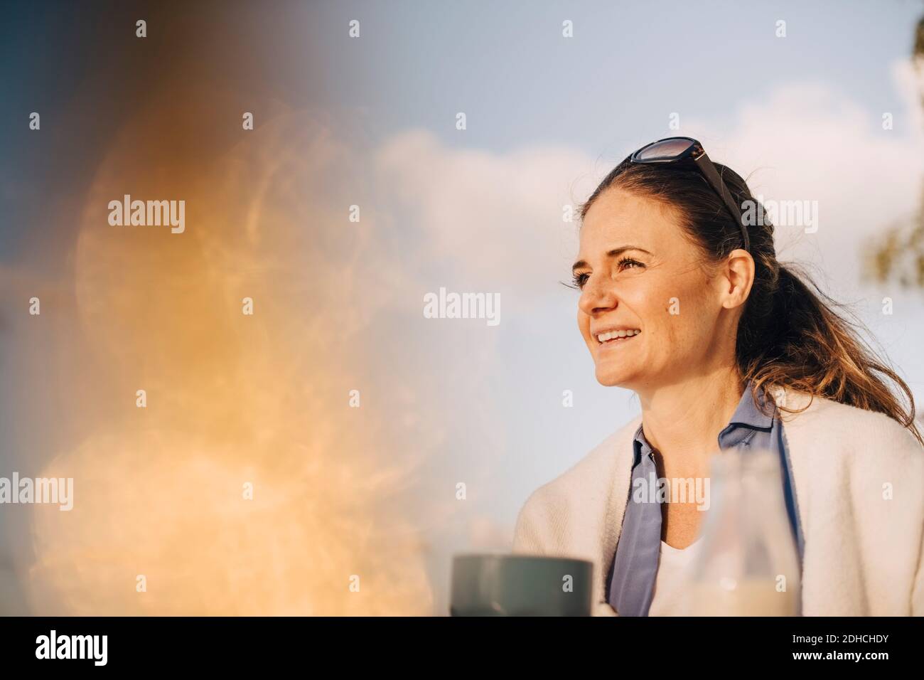 Nahaufnahme einer nachdenklichen Frau, die Kaffee gegen den Himmel hat Stockfoto