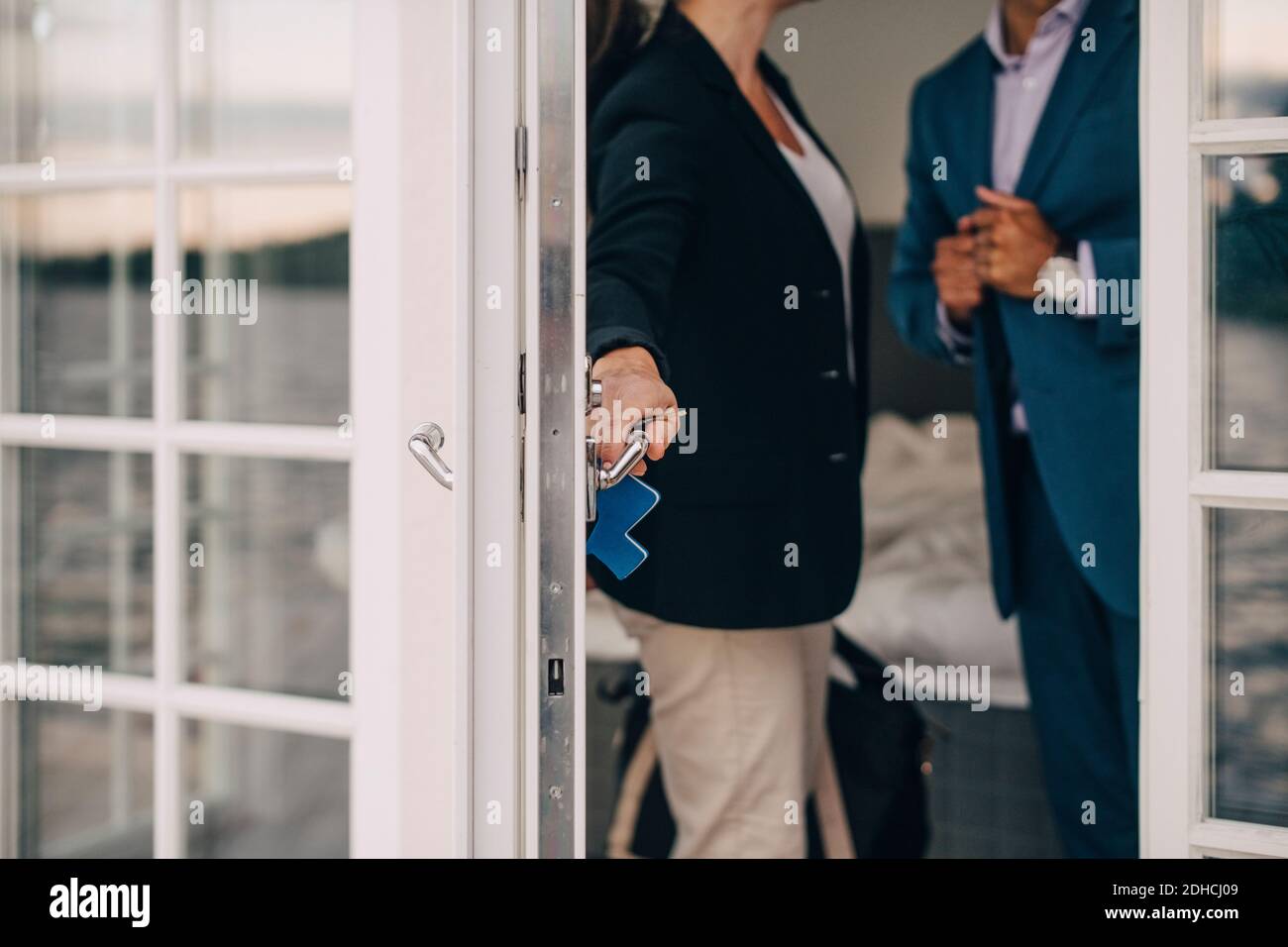 Mittelteil eines reifen Paares, das die Glastür in der Ferienvilla verriegelt Stockfoto