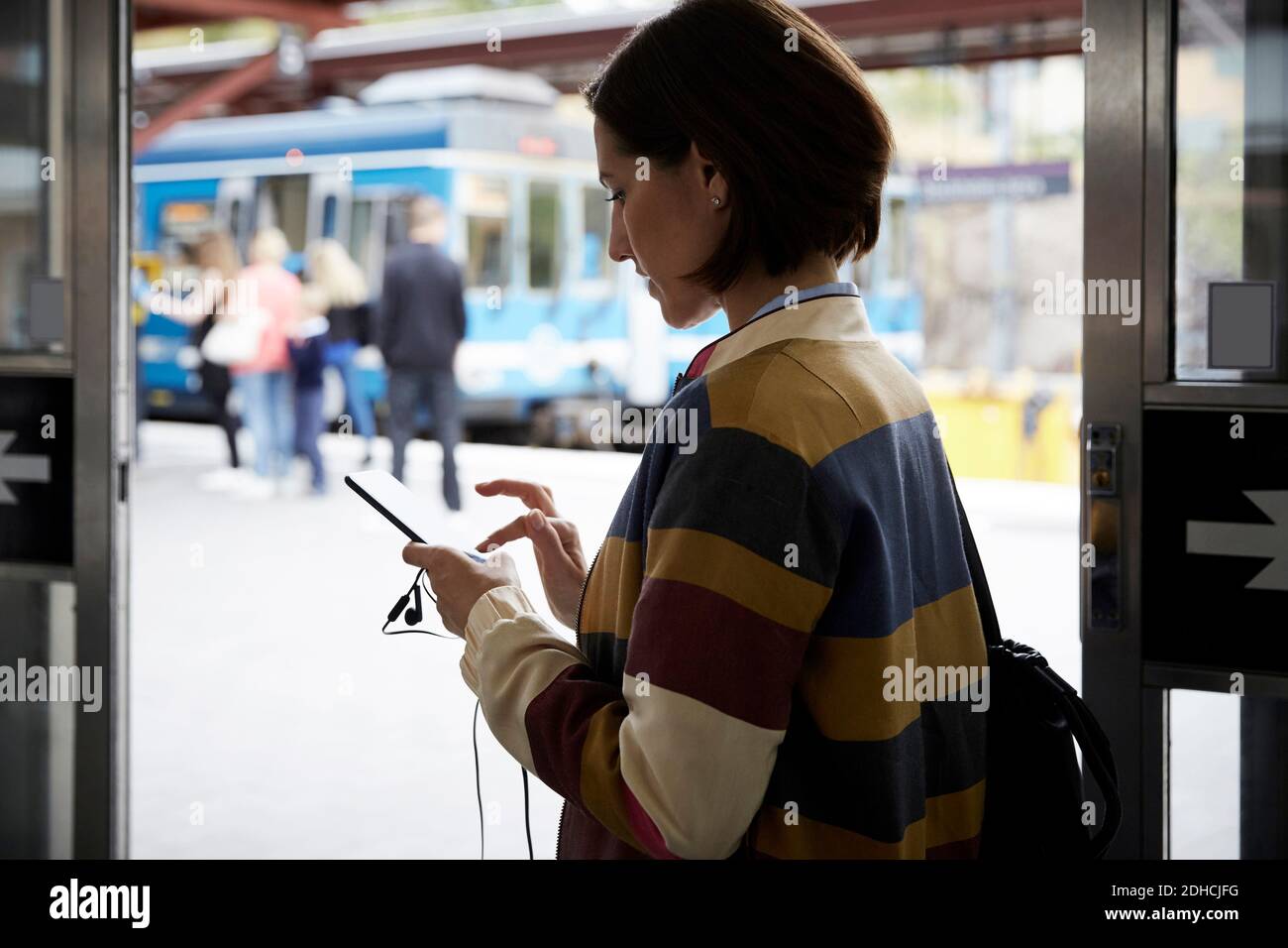 Geschäftsfrau, die Smartphone benutzt, während sie im Bahnhof steht Stockfoto