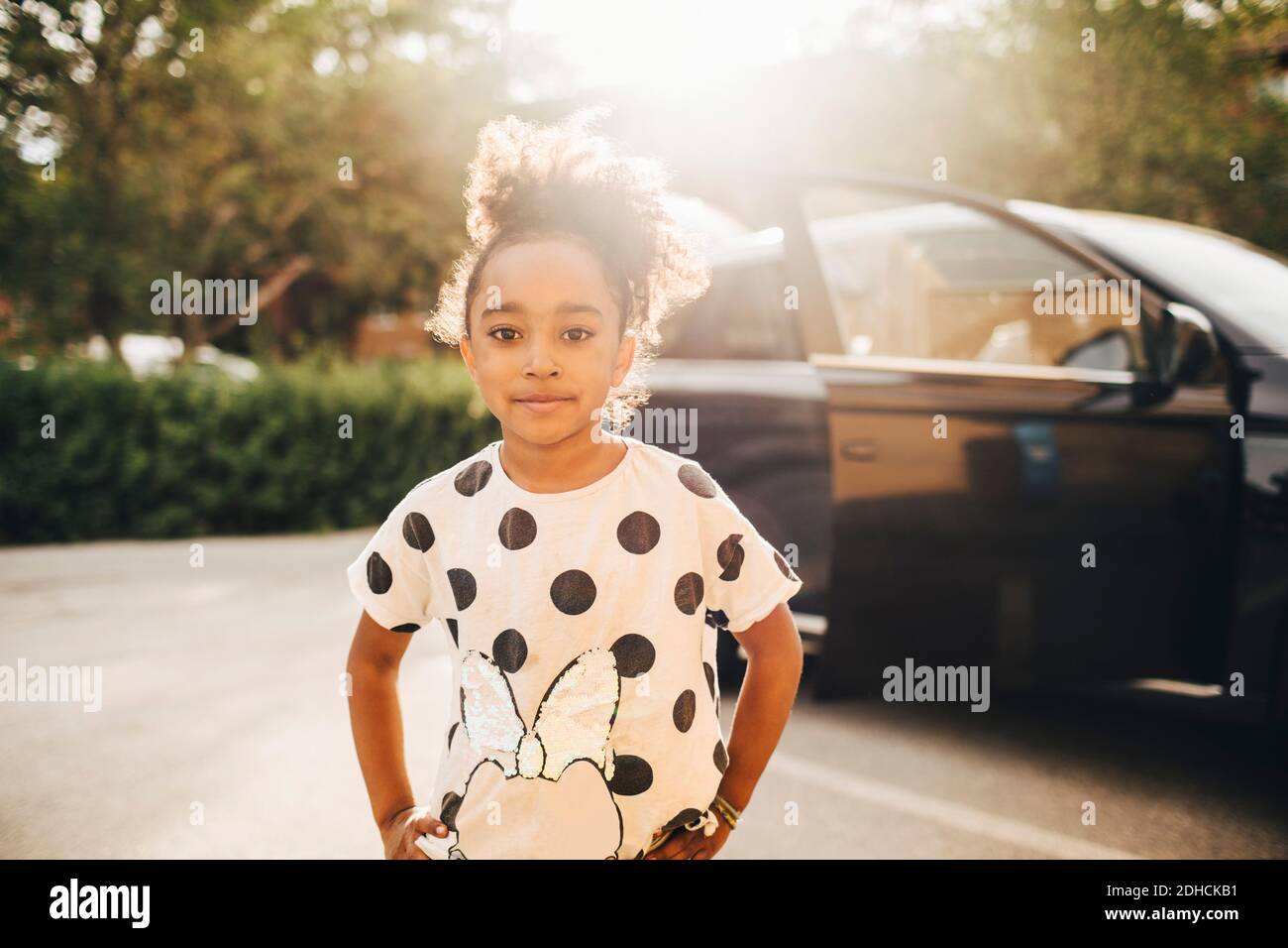 Porträt eines Mädchens, das auf der Auffahrt gegen ein Elektroauto steht Stockfoto