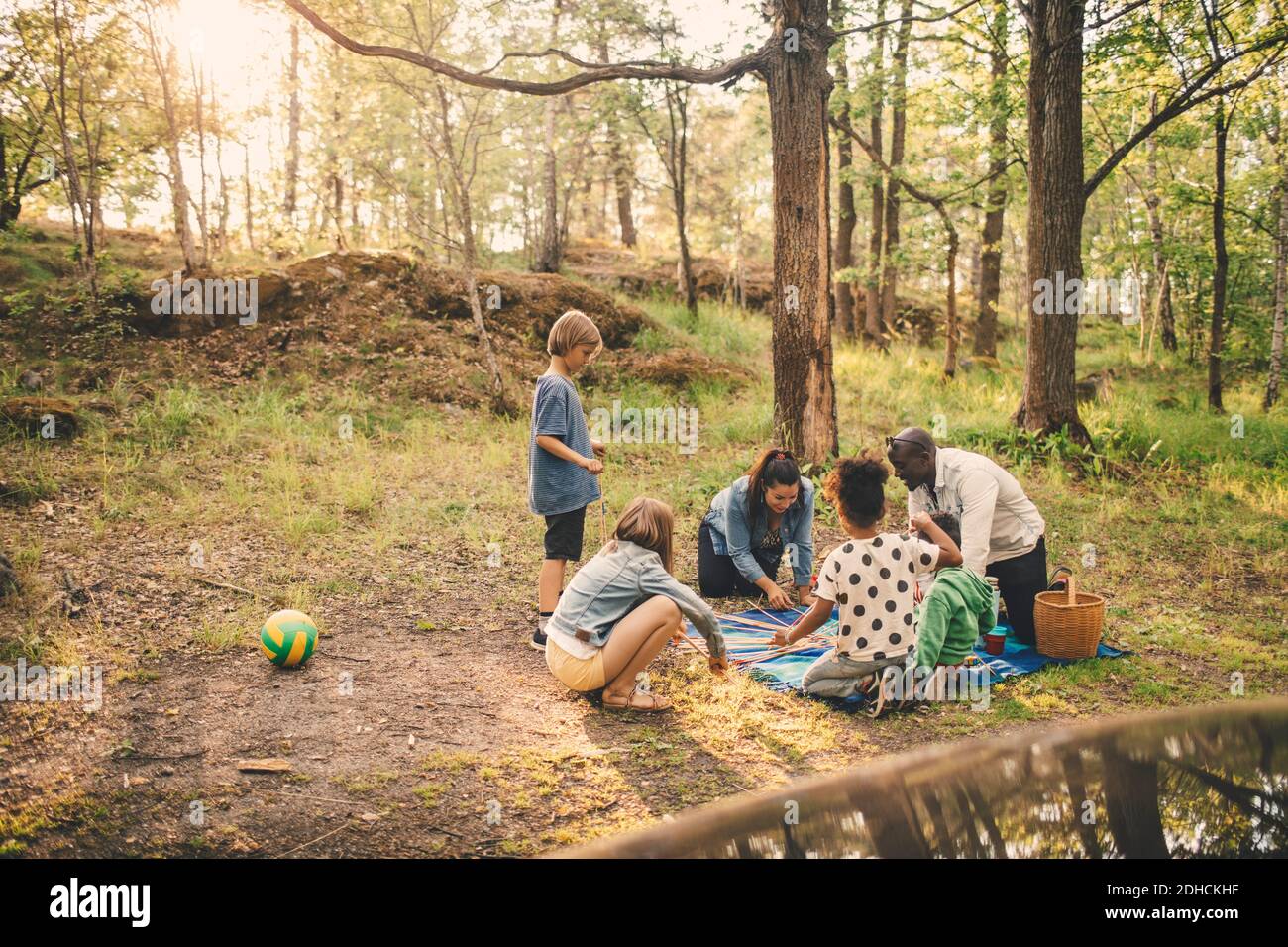 Multiethnische Familie genießt Picknick gegen Bäume im öffentlichen Park Stockfoto