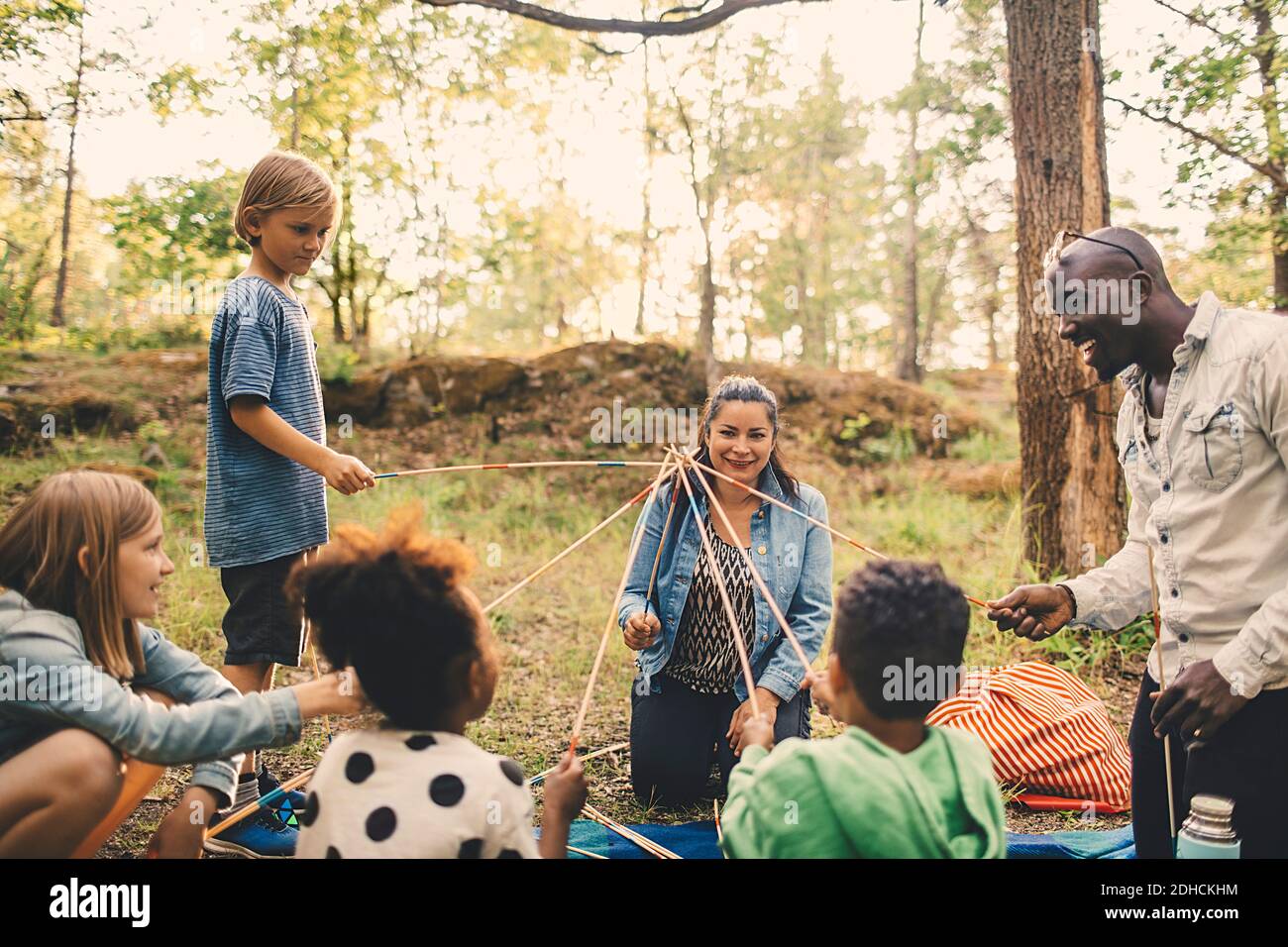 Multiethnische Familie spielt mit Spiessen am Picknickplatz im Park Stockfoto