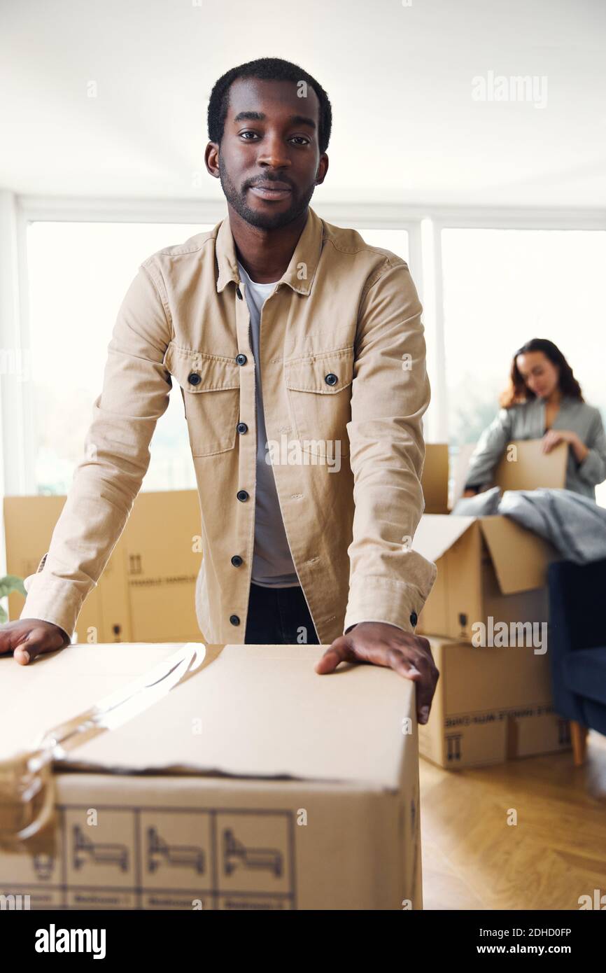 Porträt von jungen gemischten ethnischen Zugehörigkeit Paar stehend in der Lounge von Neues Zuhause Auspacken Umzugskartons zusammen Stockfoto