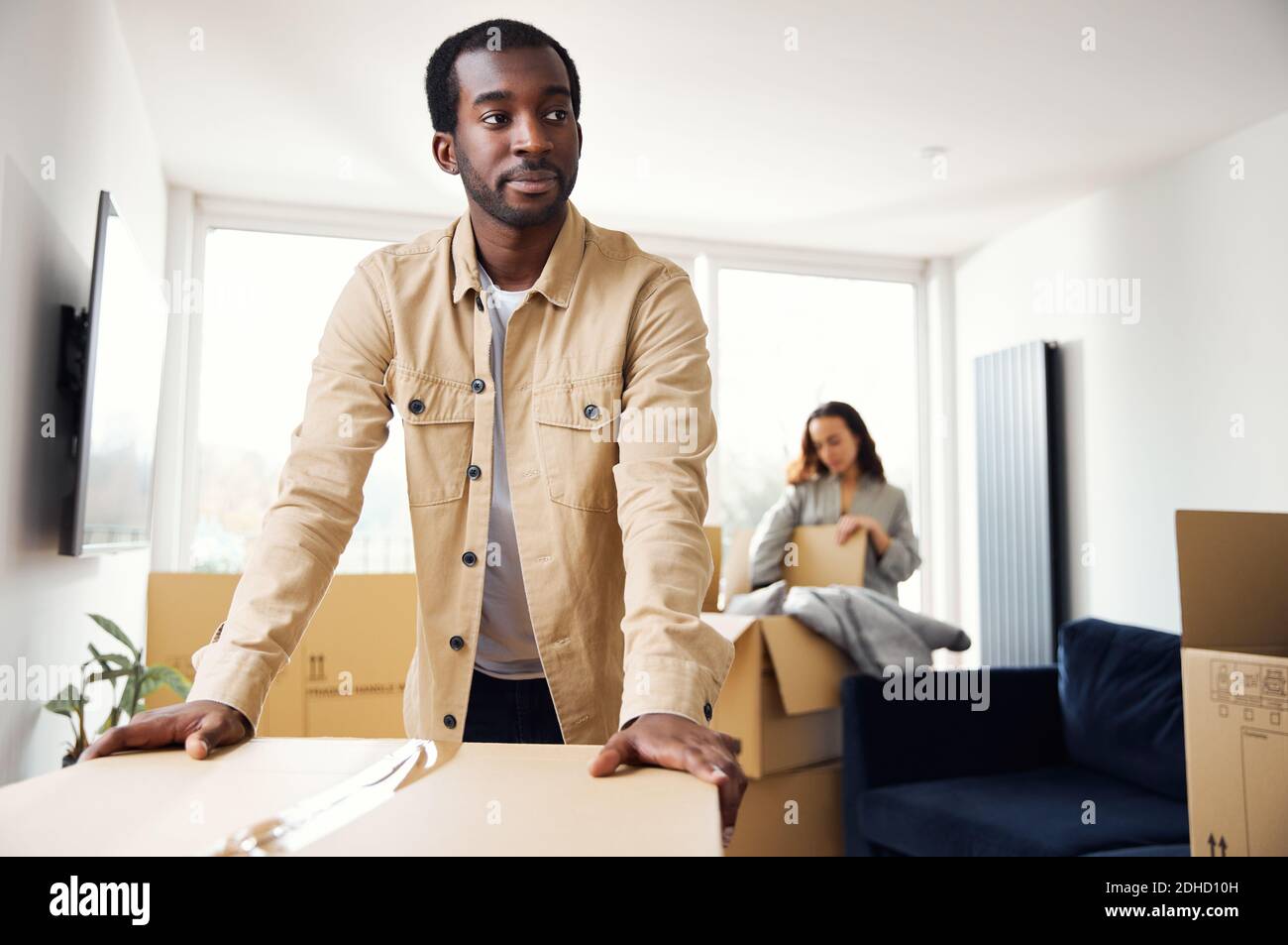 Porträt von jungen gemischten ethnischen Zugehörigkeit Paar stehend in der Lounge von Neues Zuhause Auspacken Umzugskartons zusammen Stockfoto