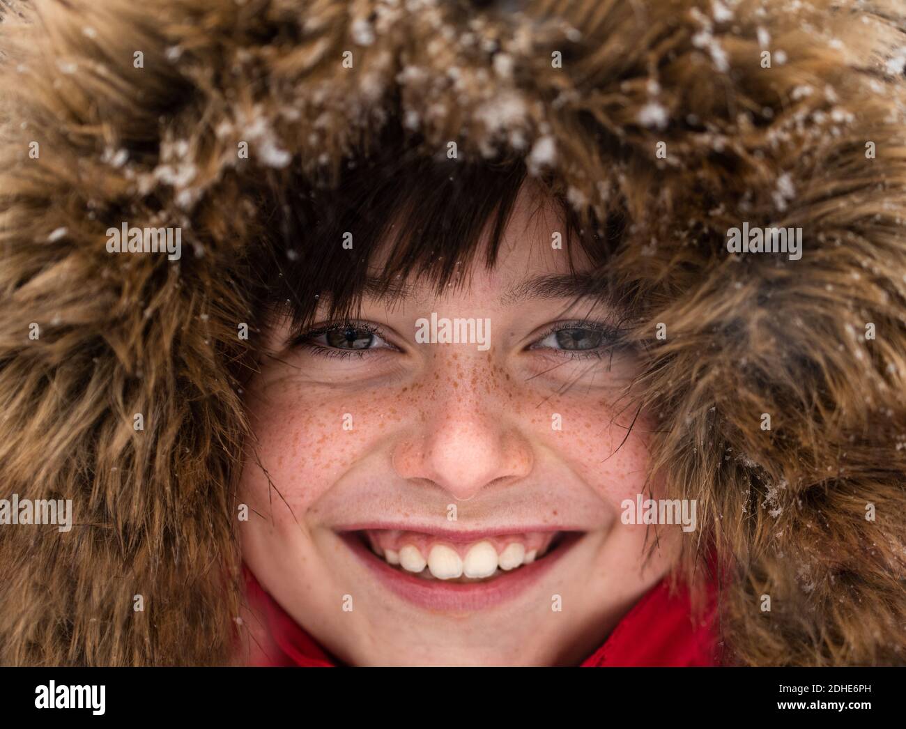 Nahaufnahme von niedlichen lächelnden Jungen in Pelzbesatz Kapuze an einem verschneiten Tag. Stockfoto
