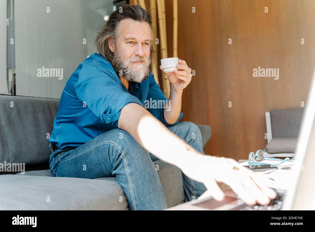 Reifer Mann mit einem Bart, der eine Tasse Kaffee trinkt Und auf einer Vide reden Stockfoto