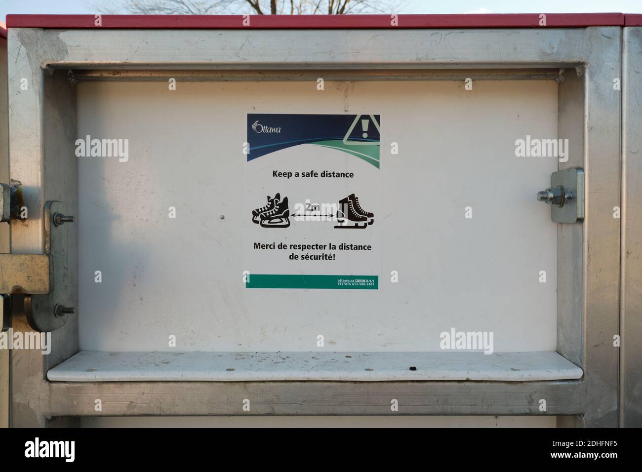 Ottawa, Kanada. Dezember. 2020. Öffentliche Gesundheit Zeichen während Covid Pandemie auf Eisbahn sagen, zwei Meter mit Bild von Schlittschuhen zu bleiben Stockfoto