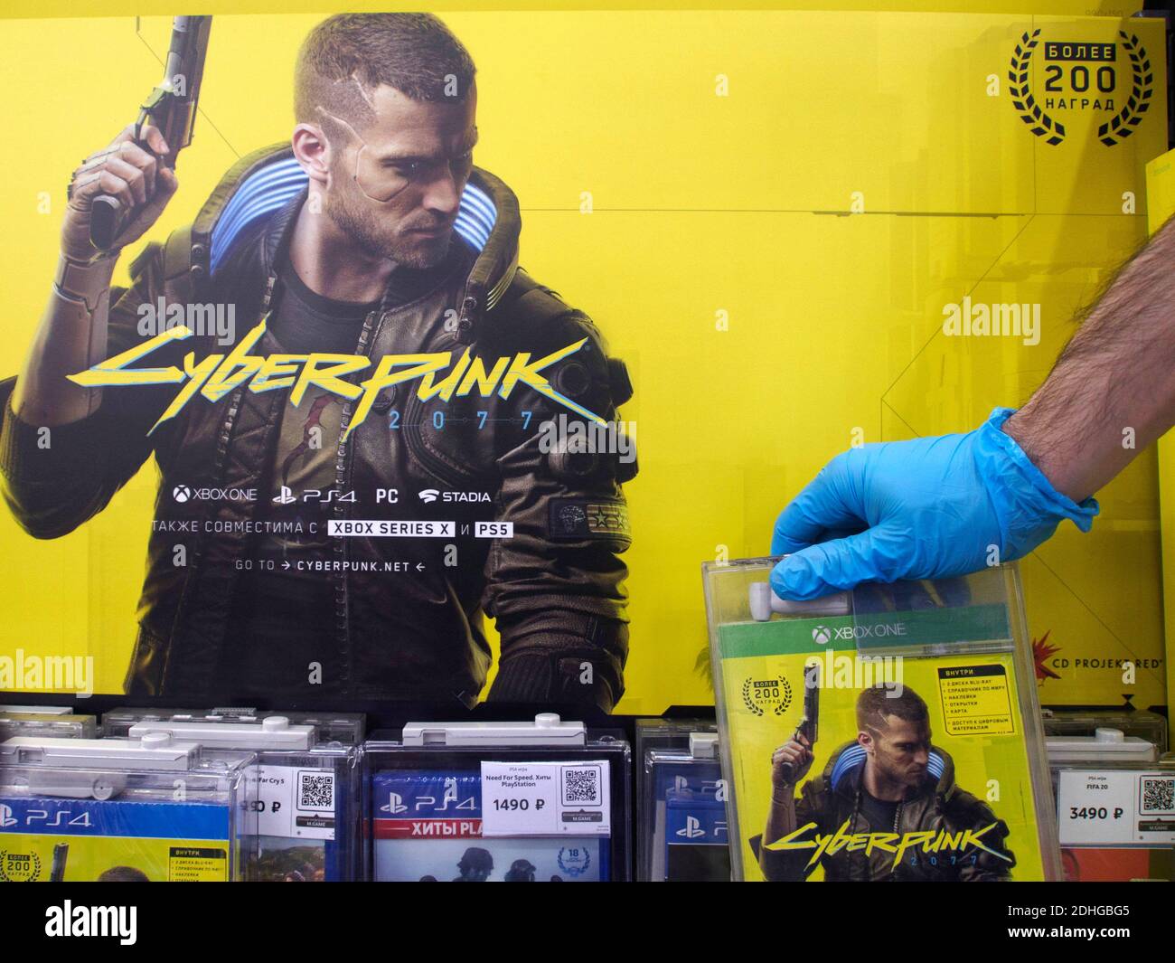 Moskau, Russland. Dezember 2020. Ein Arbeiter trägt einen Handschuh zeigt eine Spieldisc auf dem Regal.Cyberpunk 2077 ist ein 2020-Action-Rollenspiel, das weltweit verkauft wird. In Russland ist es das am meisten erwartete Spiel im Jahr 2020 geworden. Kredit: SOPA Images Limited/Alamy Live Nachrichten Stockfoto