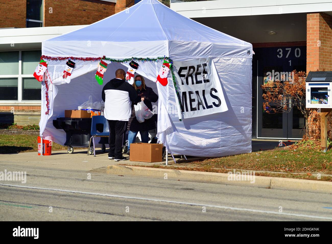 South Elgin, Illinois, USA. Mann pflücken Beutel mit Lebensmitteln in einer lokalen Schule, die kostenlose Mahlzeiten. Stockfoto
