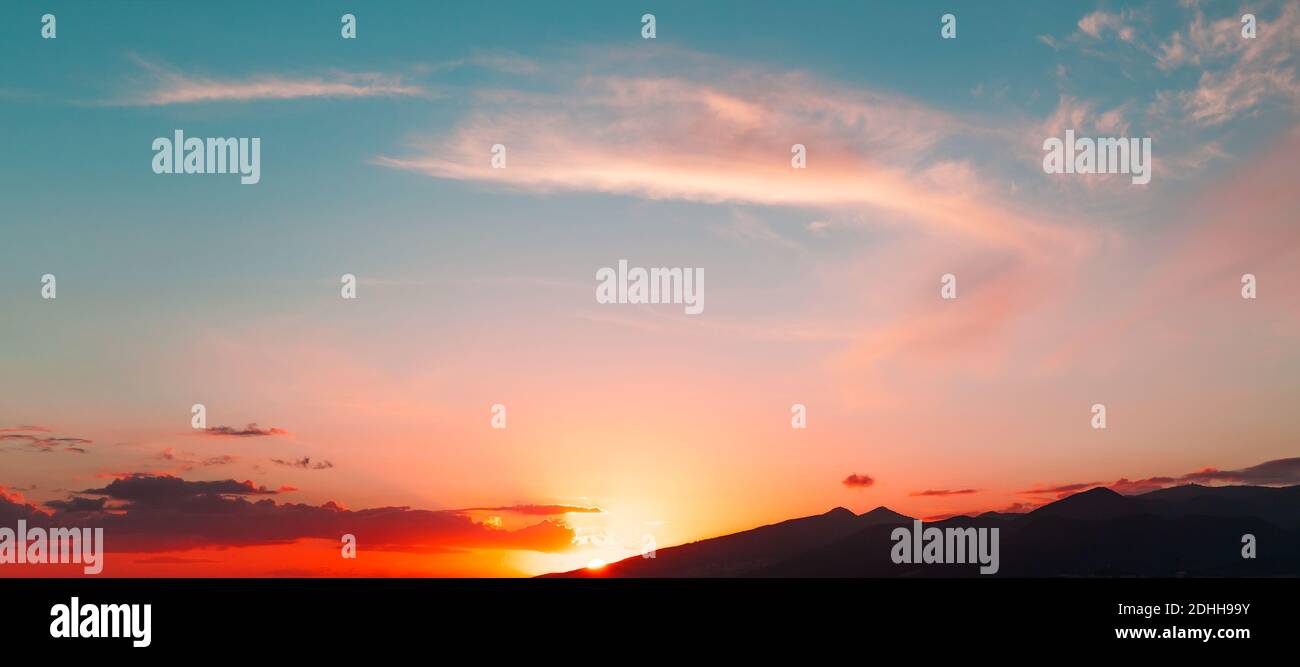 Bunte Wolke bei Sonnenuntergang, Panorama-Hintergrund-Foto mit hellen Wolken über Bergen Stockfoto