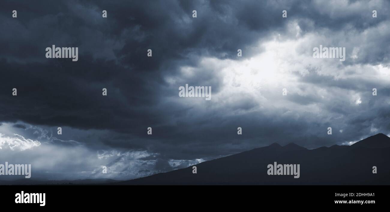 Dunkelblauer dramatischer Himmel mit stürmischen Wolken über den Bergen, natürliches Panorama-Hintergrundbild Stockfoto