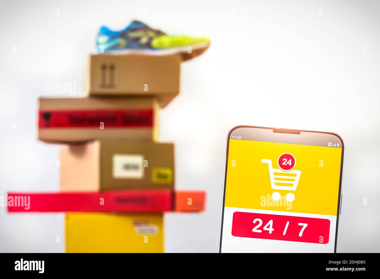Screenshot einer Mobile Shopping App mit den Nummern 24 7 und Stapel von Paketen im Hintergrund Stockfoto