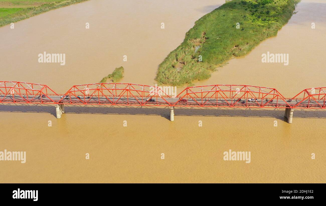 Autos fahren auf der Brücke. Breiten Fluss auf der Insel Luzon, Philippinen, Luftbild. Brücke über den Fluss. Landschaft, landwirtschaftliche Felder in der Nähe des Flusses. Stockfoto