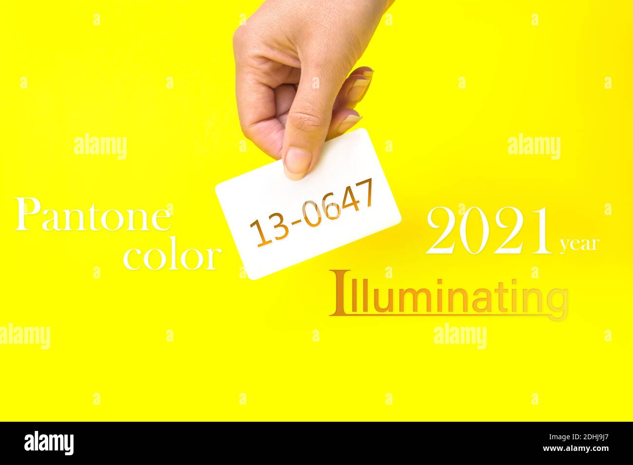 Pantone Farbe des Jahres 2021. Visitenkarte in der Hand mit Text 13-0647, beleuchtet auf gelbem Hintergrund. Farbtrend. Leuchtet Stockfoto