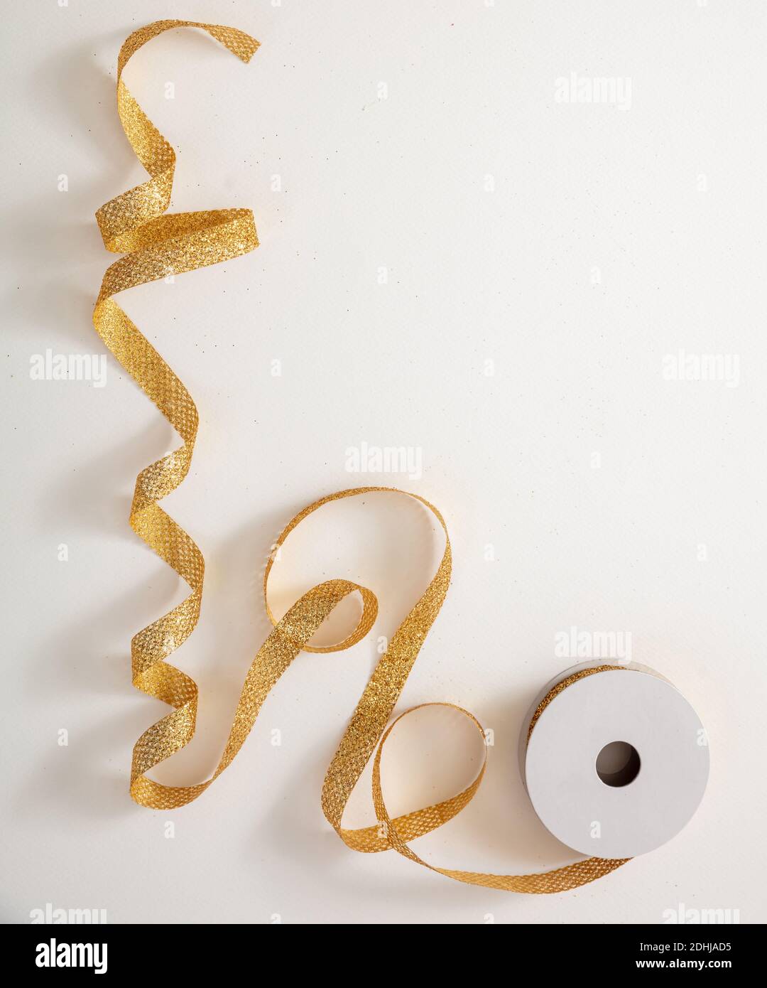 Weihnachten Geschenke hausgemachte Verpackung, Urlaub Vorbereitung. Glänzend Gold Band Verpackung Dekoration und Spule isoliert auf weißem Hintergrund, Draufsicht. Stockfoto