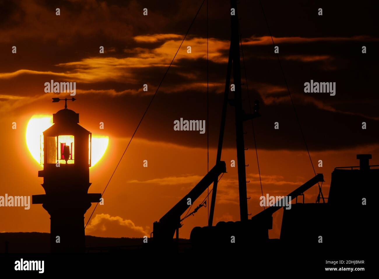 Die Ruhe vor Storm Alex, wenn die Sonne hinter dem Penzance Harbour Leuchtturm am ersten Oktobertag aufgeht. Stockfoto
