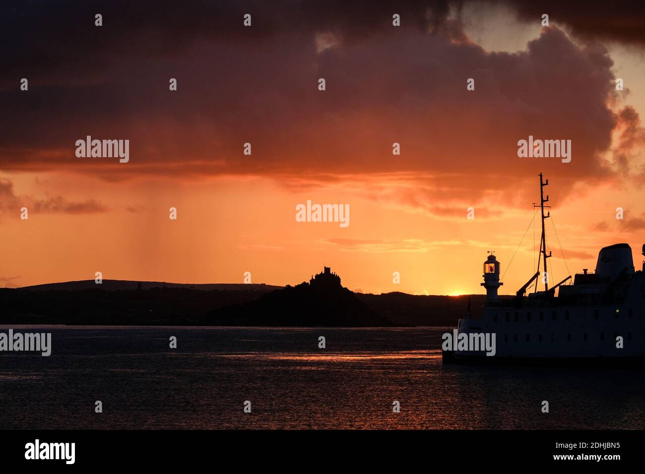 Die Ruhe vor Storm Alex, wenn die Sonne hinter dem Penzance Harbour Leuchtturm am ersten Oktobertag aufgeht. Stockfoto