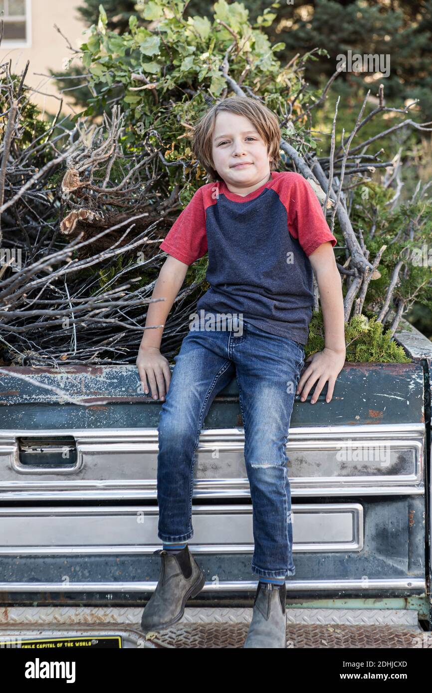Kleiner Junge, der auf einem alten Pick-up-Truck voller sitzt Reisig Stockfoto