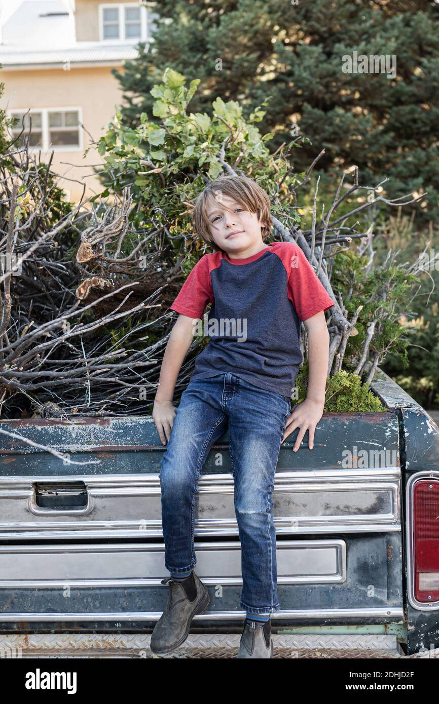 Kleiner Junge, der auf einem alten Pick-up-Truck voller sitzt Reisig Stockfoto