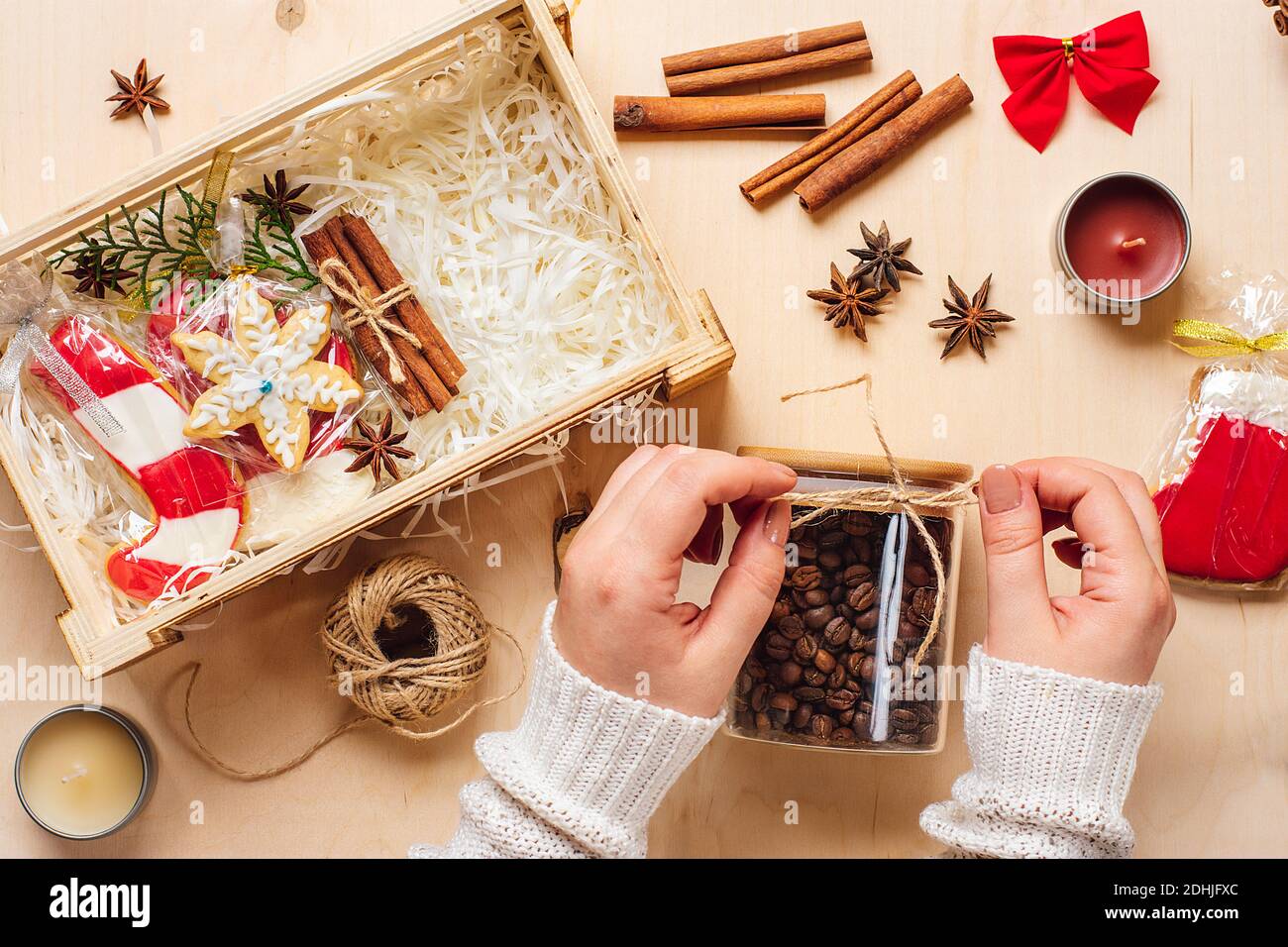 Weibliche Hände gelegt Pflege-Paket, saisonale Geschenkbox mit Kaffee, Lebkuchen und Zimt Personalisierte umweltfreundliche Korb für Familie, Freunde für danke Stockfoto