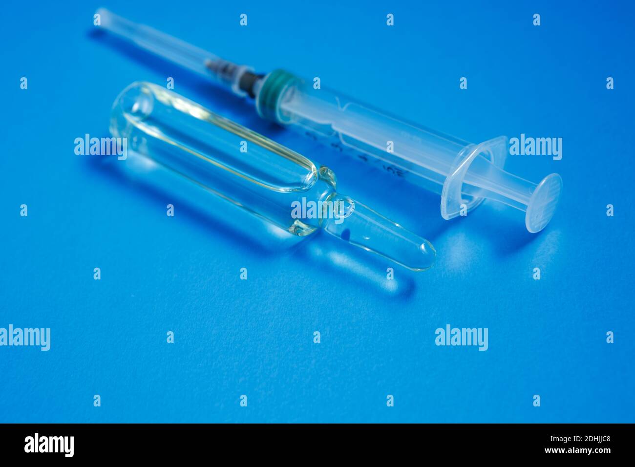 Eine Ampulle mit einem Impfstoff und einer Spritze sind auf blauem Hintergrund. Das Konzept der Impfung gegen Coronavirus. Stockfoto