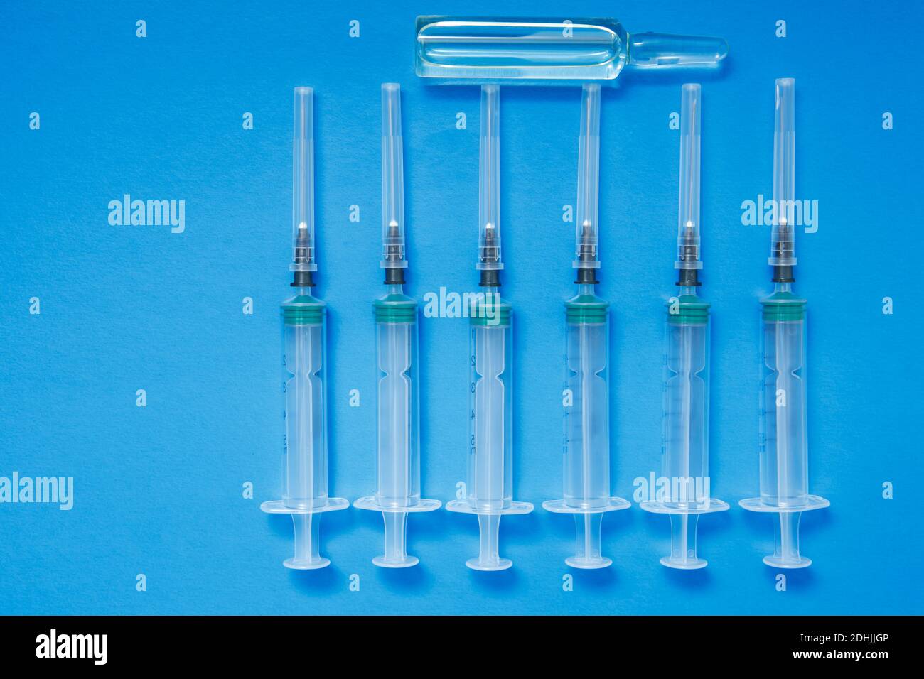 Eine Ampulle mit einem Impfstoff und Spritzen auf blauem Hintergrund. Das Konzept der Impfung gegen Coronavirus. Stockfoto