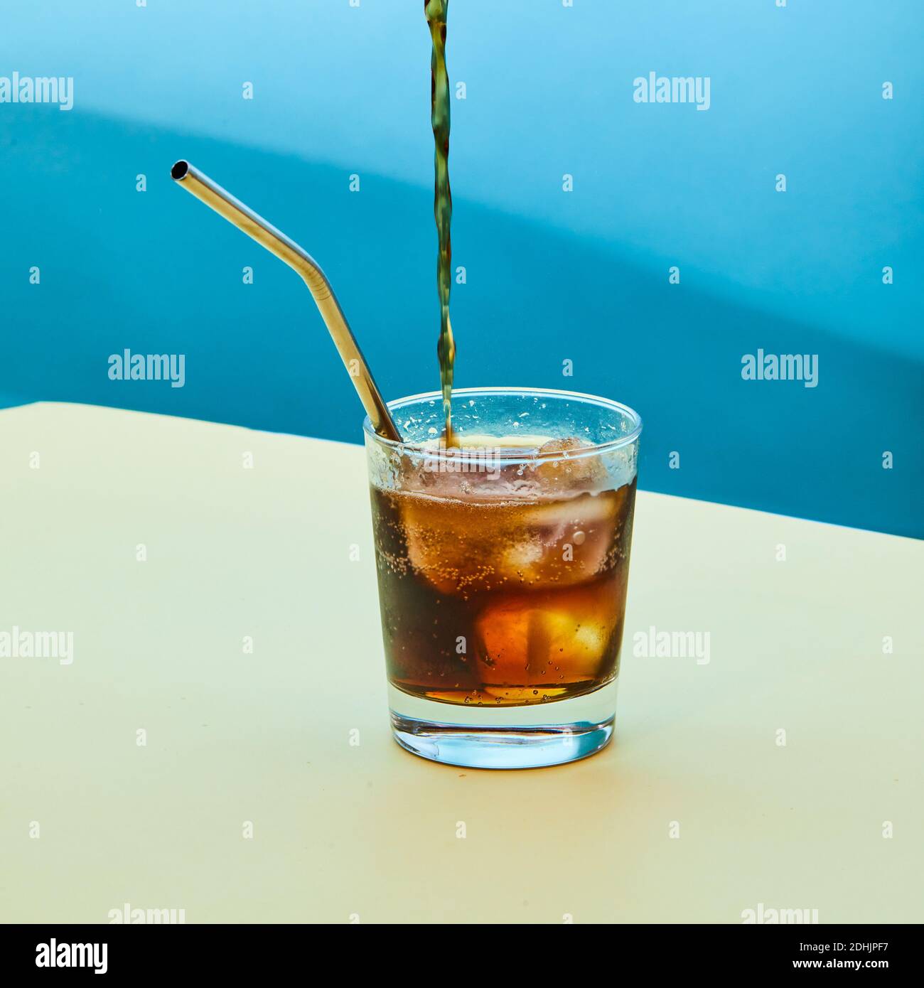 Erfrischende kalte Cola Gießen in Glas mit wiederverwendbarem Metallstroh  Und Eiswürfel auf dem Tisch im Studio platziert und zeigen Zero Waste  Konzept Stockfotografie - Alamy