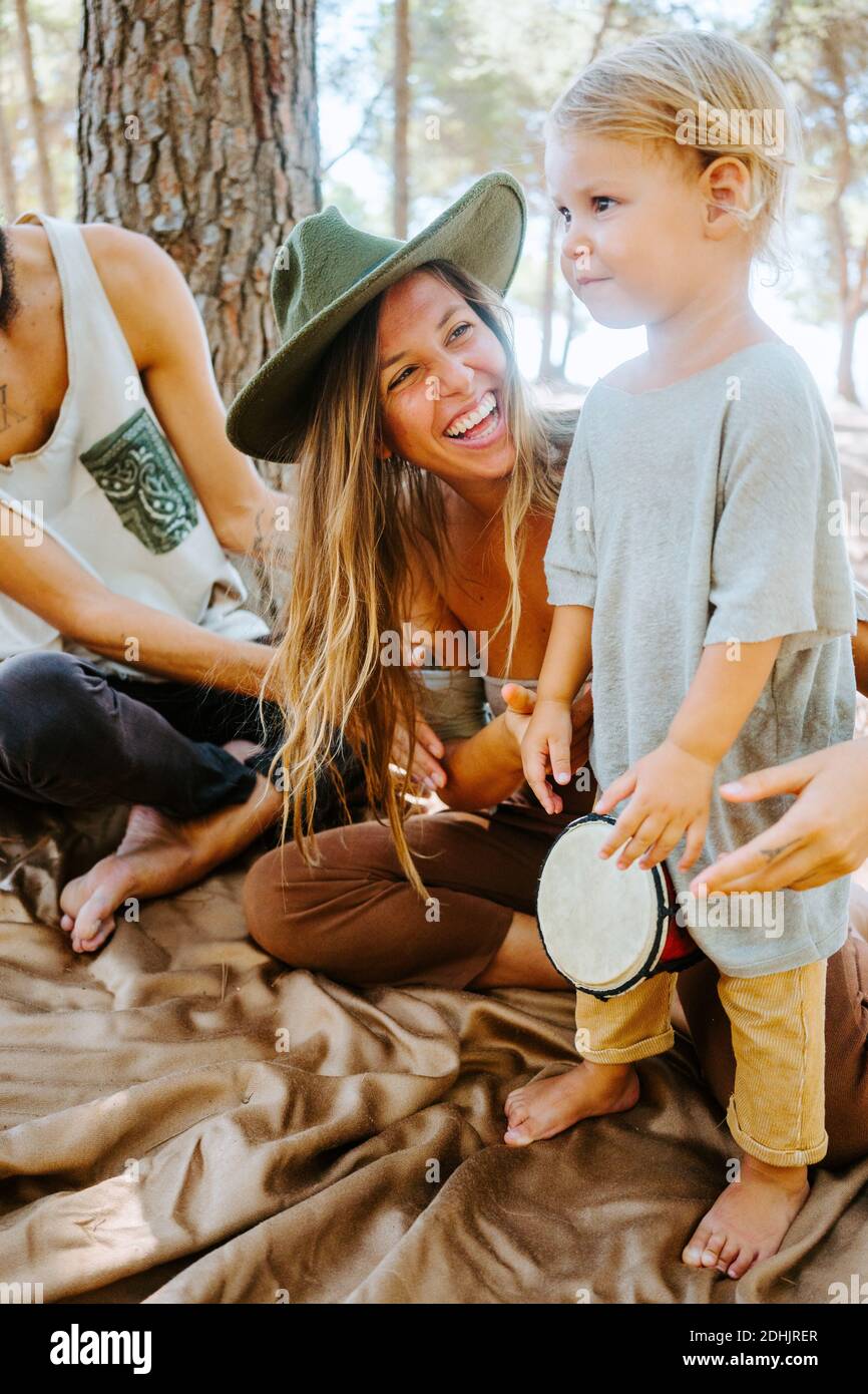 Entzückte Mutter und Ernte Vater unterrichtet kleine Kind spielen Bongo Trommeln Sie, während Sie Zeit zusammen im Wald verbringen Stockfoto