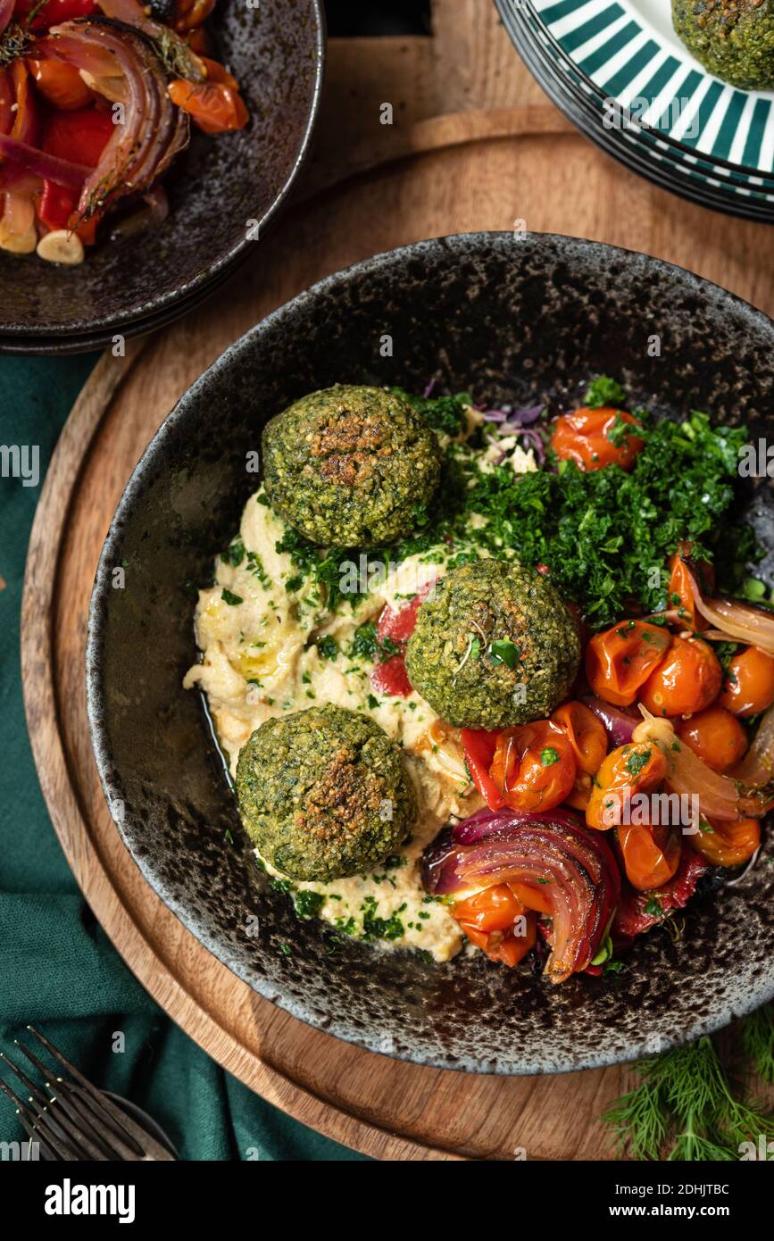 Draufsicht auf traditionelle Gerichte aus dem Nahen Osten mit vegetarischem Hummus Und Falafel serviert mit Gemüse und grünen Kräutern während des Abendessens Stockfoto