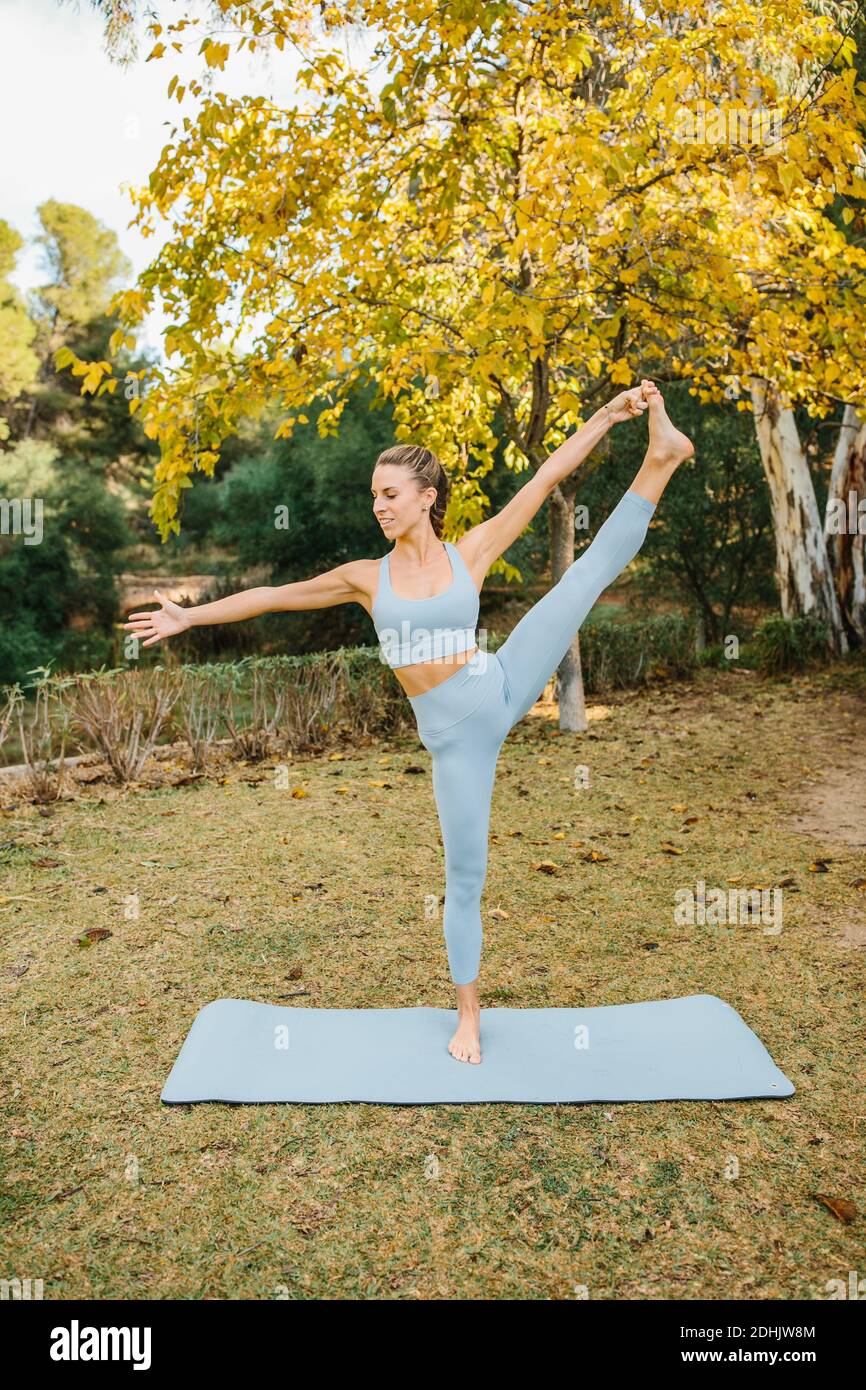 Ganzer Körper der jungen schlanken weiblichen tun Extended stehende Hand Zu Toe Asana während des Übens fortgeschrittenen Yoga im Park Stockfoto